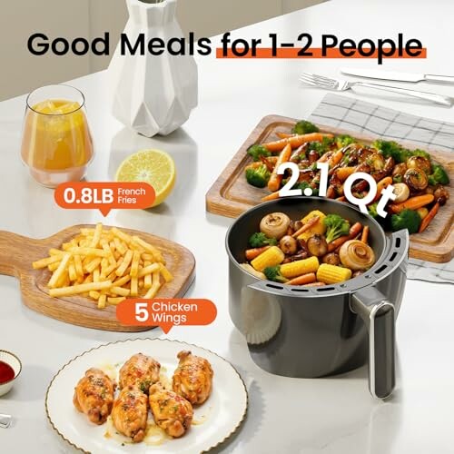Air fryer with cooked vegetables, chicken wings, fries, and juice.