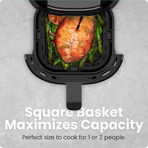 Air fryer with square basket containing salmon and asparagus