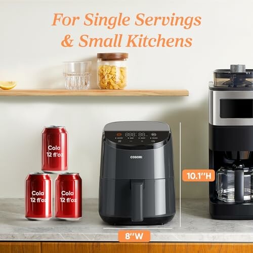 Compact air fryer in a small kitchen with cola cans and coffee maker