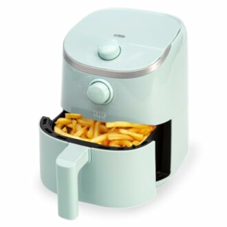 Mint green air fryer with fries inside.