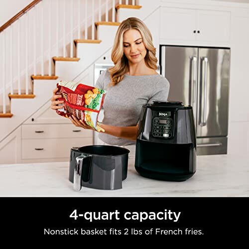 Woman placing food in an air fryer on a kitchen counter.